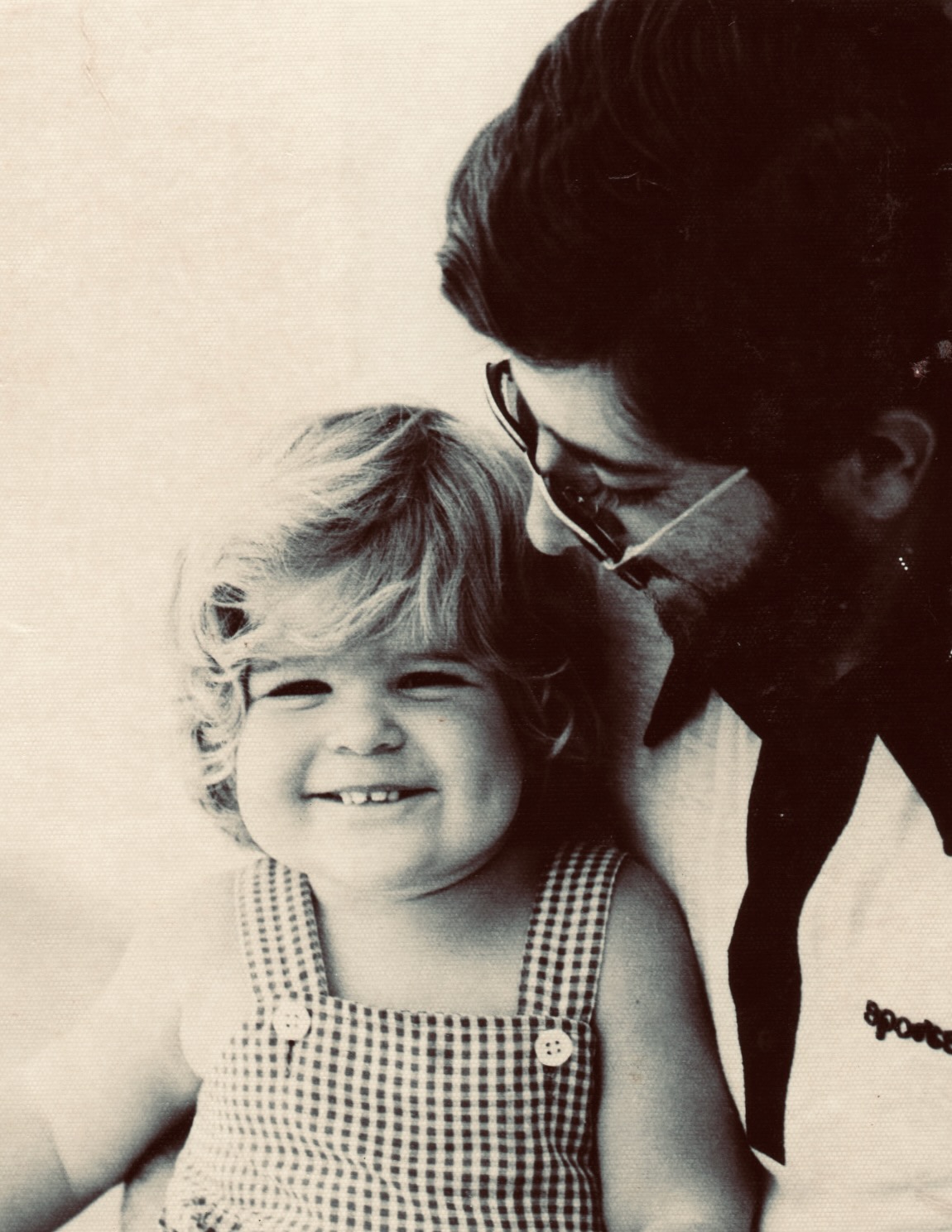 A young Andrea, smiling, with her father — a tender vintage portrait.